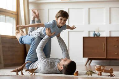 Portrait,Of,Happy,Young,Caucasian,Father,Lying,On,Floor,At