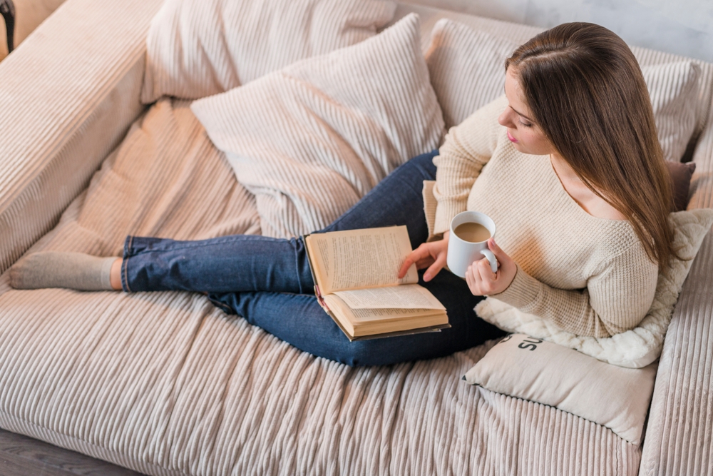 Young,Woman,Holding,Cup,Coffee,Reading,Book