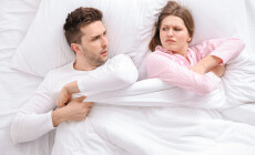 Young,Couple,Fighting,For,Blanket,In,Bed