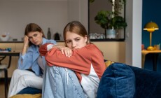 Frustrated,Teenage,Girl,Sits,Hugging,His,Knees,,Looks,Away.,Mom