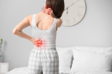 Young,Woman,Suffering,From,Back,Pain,In,Bedroom