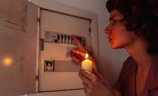 Young,Woman,With,Candles,In,Complete,Darkness,Examines,Fuse,Box