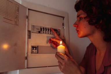 Young,Woman,With,Candles,In,Complete,Darkness,Examines,Fuse,Box