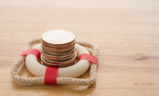 Stacked,Coins,In,Red,Lifebuoy,Or,Lifebelt,With,Wooden,Background