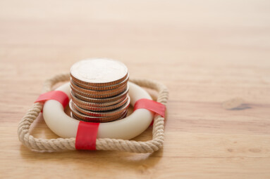 Stacked,Coins,In,Red,Lifebuoy,Or,Lifebelt,With,Wooden,Background