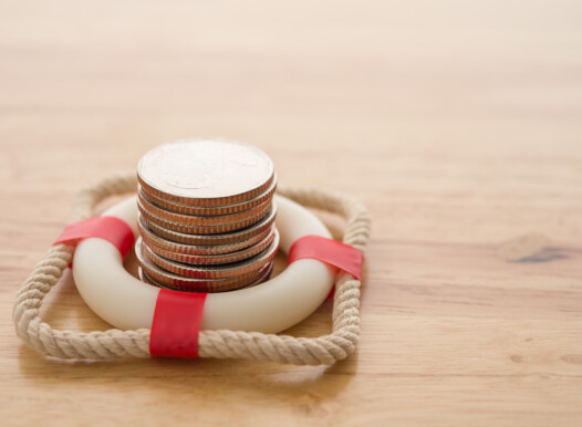 Stacked,Coins,In,Red,Lifebuoy,Or,Lifebelt,With,Wooden,Background