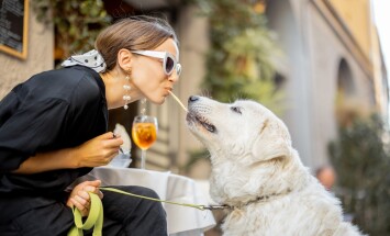 Woman,Eating,Pasta,With,Her,Cute,White,Dog,At,The