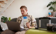 Angry,Man,Holding,His,Flight,Tickets,,Staring,Upset,At,Laptop