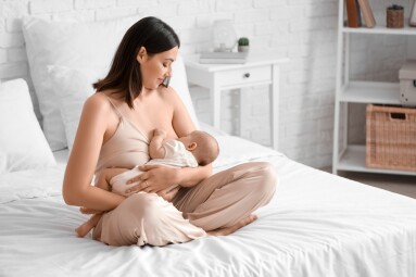 Young,Woman,Breastfeeding,Her,Baby,In,Bedroom