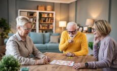 Three,Senior,Friends,Are,Gathering,Around,A,Wooden,Table,,Playing
