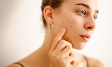 A,Woman,Touches,Her,Face,Gently,While,Inspecting,Her,Skin