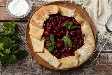 Tasty,Galette,With,Cherries,,Mint,And,Powdered,Sugar,On,Wooden