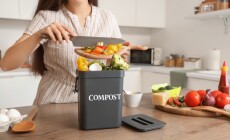 Young,Woman,Throwing,Food,Into,Container,For,Compost,In,Kitchen,