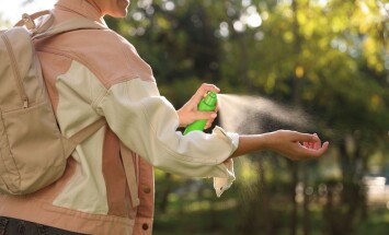 Woman,Spraying,Tick,Repellent,Onto,Hand,In,Park,,Closeup