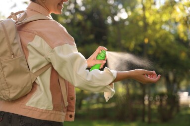 Woman,Spraying,Tick,Repellent,Onto,Hand,In,Park,,Closeup