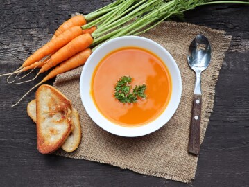 Carrot,Soup,With,Fresh,Herbs,And,Bread,On,Wooden,Table