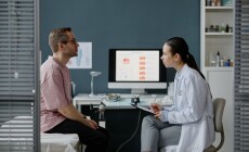 Caucasian,Middle,Aged,Man,Sitting,On,Examination,Table,Consulting,With