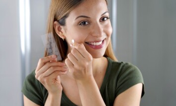 Close-up,Of,Smiling,Girl,Applying,Acne,Treatment,Anti-pickel,Patch,On