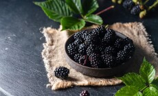Ripe,Blackberries,With,Leaves,In,A,Bowl,On,A,Dark
