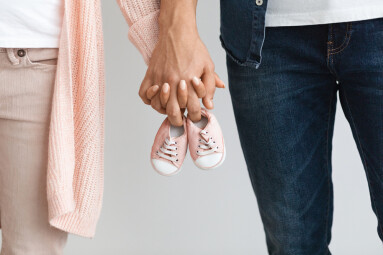 Closeup,Of,Pregnant,Couple,Carrying,Small,Baby,Shoes,While,Holding