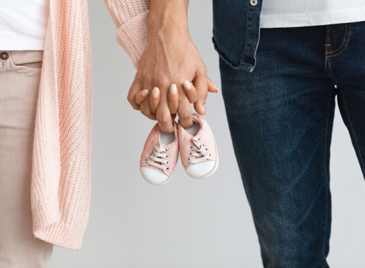 Closeup,Of,Pregnant,Couple,Carrying,Small,Baby,Shoes,While,Holding