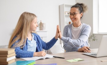 Little,Girl,With,Tutor,Giving,Each,Other,High-five,At,Home