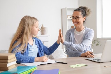 Little,Girl,With,Tutor,Giving,Each,Other,High-five,At,Home