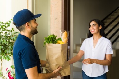Smiling,Delivery,Man,Holding,A,Paper,Bag,With,Groceries,And