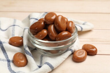 Many,Tasty,Caramel,Candies,On,White,Wooden,Table,,Closeup