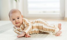 Smiling,Infant,In,Striped,Pajamas,Lying,On,Side,,Learning,To