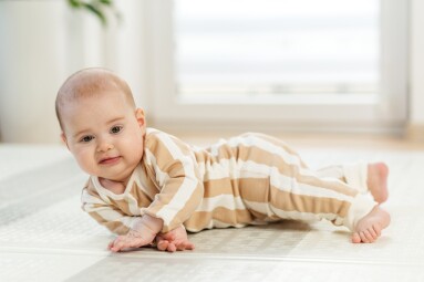 Smiling,Infant,In,Striped,Pajamas,Lying,On,Side,,Learning,To
