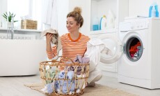 Happy,Woman,With,Laundry,Near,Washing,Machine,Indoors