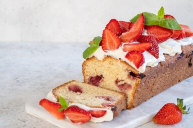 A,Loaf,Cake,Topped,With,Fresh,Strawberries,And,Mint,Sits