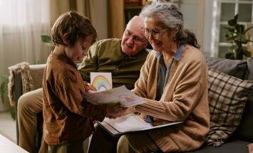 Senior,Grandparents,Smiling,And,Reviewing,Childs,Drawing,With,Young,Boy