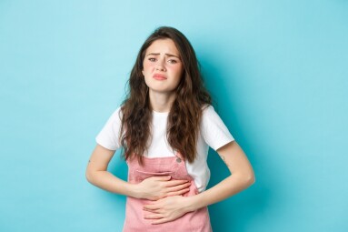 Image,Of,Sad,Young,Woman,Frowning,,Holding,Hands,On,Stomach,