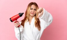 Teenager,Blonde,Girl,Holding,A,Hairdryer,Over,Isolated,Pink,Background