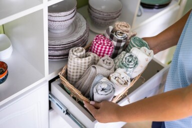 Woman,Placing,Kitchen,Textile,Towel,Roll,In,Whicked,Basket,Shelf